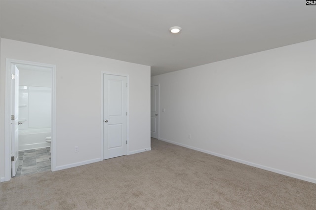 unfurnished bedroom with ensuite bath and light carpet