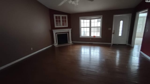 unfurnished living room with vaulted ceiling, ceiling fan, and dark wood-type flooring