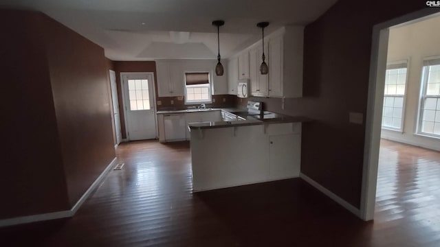 kitchen with white cabinets, white appliances, kitchen peninsula, and a wealth of natural light