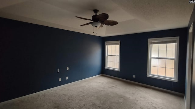 spare room with a tray ceiling, ceiling fan, carpet flooring, and a textured ceiling