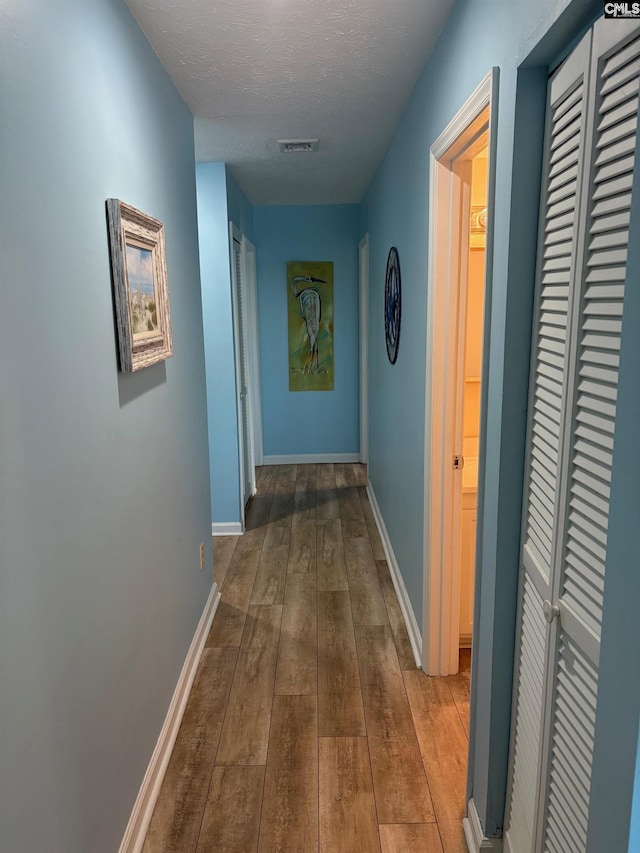 hall featuring hardwood / wood-style floors and a textured ceiling