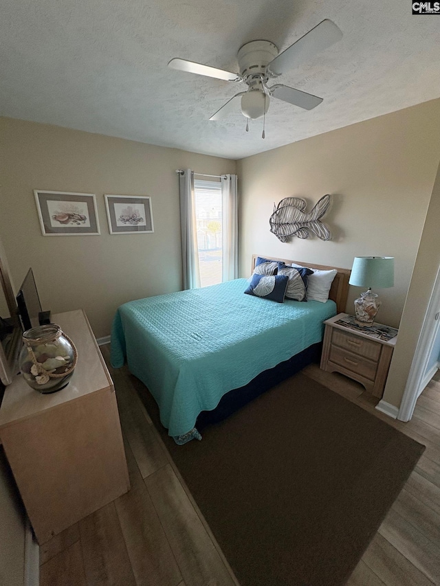 bedroom with hardwood / wood-style floors, ceiling fan, and a textured ceiling