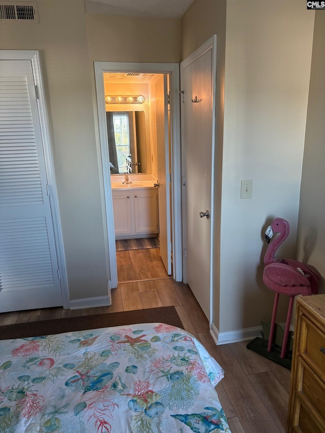 bedroom featuring sink, connected bathroom, and light hardwood / wood-style flooring