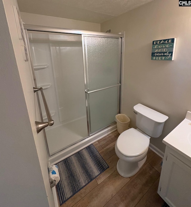 bathroom with an enclosed shower, vanity, a textured ceiling, hardwood / wood-style floors, and toilet