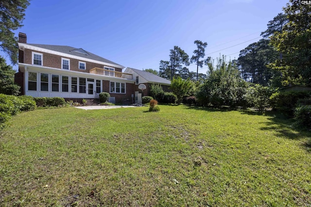 rear view of property featuring a sunroom and a lawn