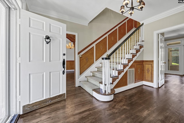 entrance foyer featuring ornamental molding, dark hardwood / wood-style floors, and an inviting chandelier