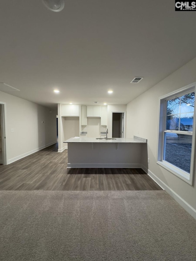 kitchen with kitchen peninsula, white cabinetry, sink, and dark colored carpet