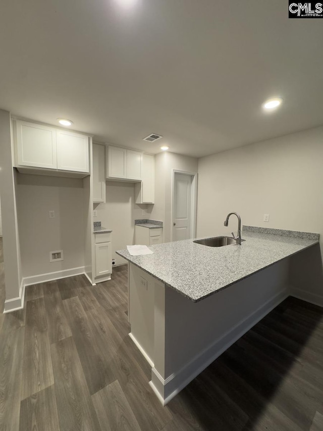 kitchen with white cabinets, dark hardwood / wood-style floors, kitchen peninsula, and sink