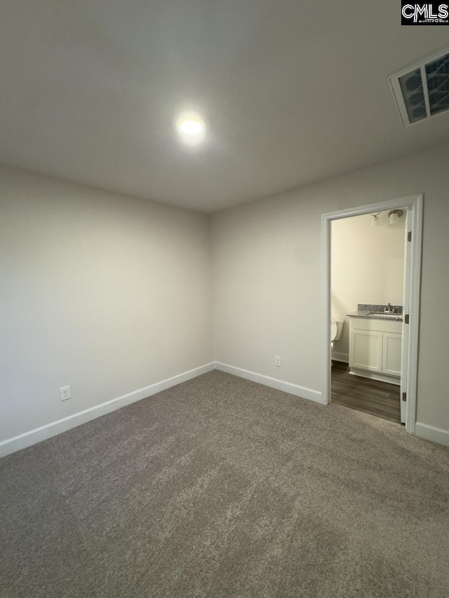 spare room featuring dark carpet and sink