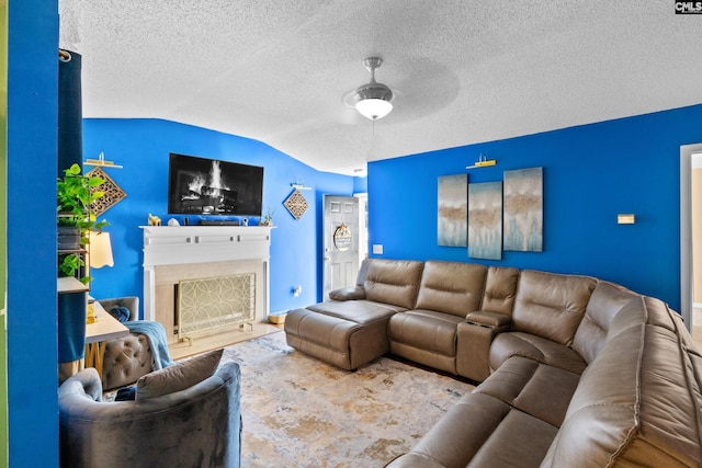 living room featuring ceiling fan, lofted ceiling, and a textured ceiling