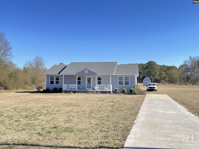 single story home with a garage, an outbuilding, a front yard, and covered porch