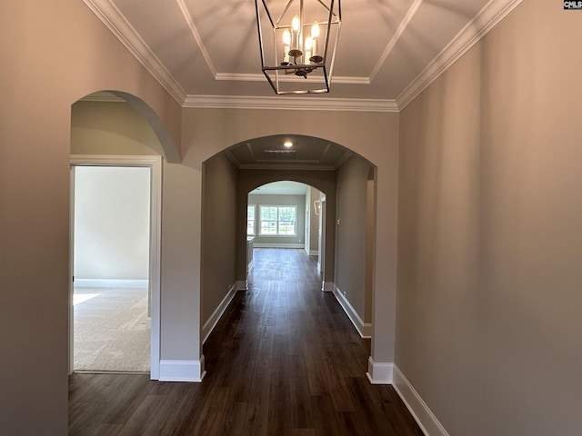 hall featuring a raised ceiling, crown molding, dark wood-type flooring, and a notable chandelier