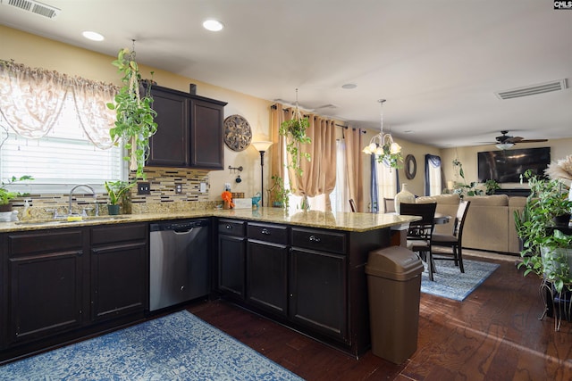 kitchen featuring stainless steel dishwasher, tasteful backsplash, dark wood-type flooring, ceiling fan with notable chandelier, and sink