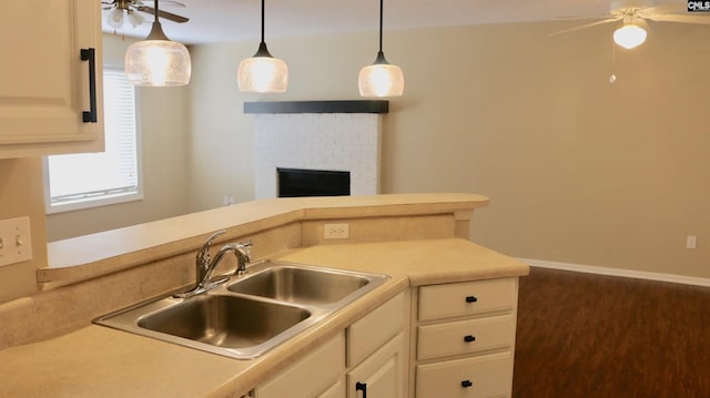 kitchen featuring a ceiling fan, light countertops, a sink, and decorative light fixtures