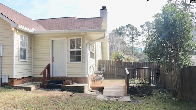 rear view of property with roof with shingles, a chimney, entry steps, fence, and a wooden deck