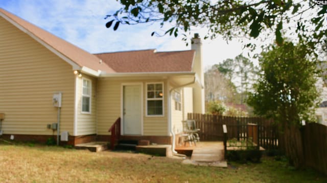 back of property with a yard, a chimney, entry steps, fence, and a deck