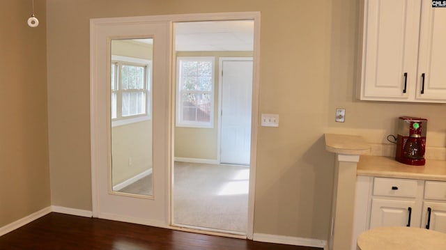 kitchen featuring dark wood-type flooring, light countertops, white cabinetry, and baseboards