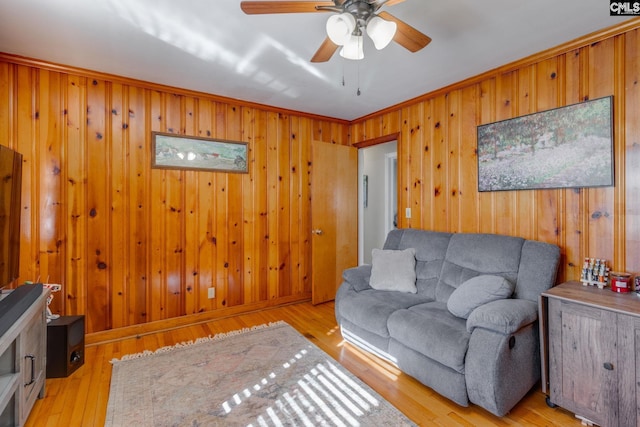 living room with ceiling fan, ornamental molding, and light hardwood / wood-style flooring