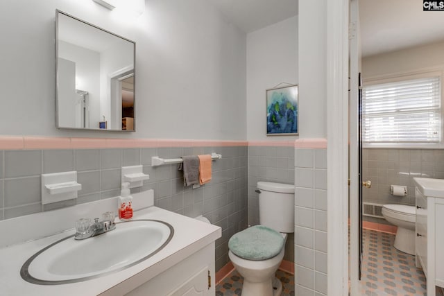 bathroom with tile patterned floors, vanity, toilet, and tile walls