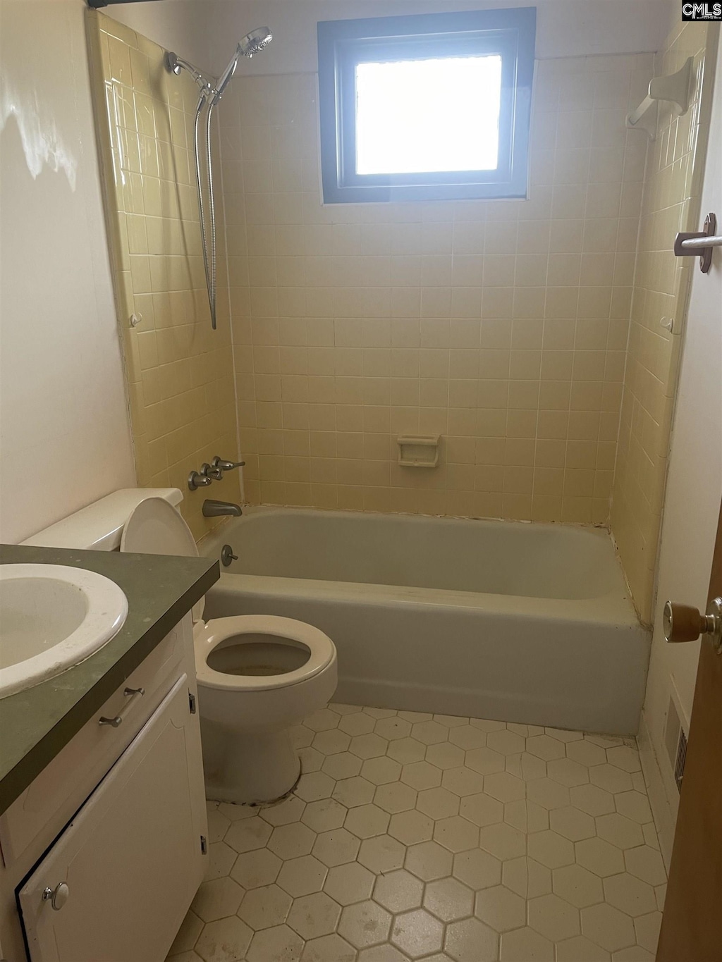 full bathroom with tile patterned flooring, tiled shower / bath combo, toilet, and vanity