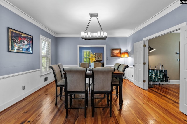 dining room featuring hardwood / wood-style floors, ornamental molding, and a notable chandelier