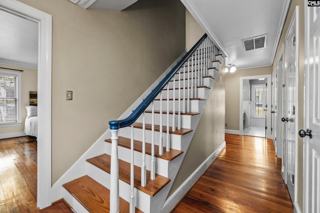 staircase featuring ornamental molding and wood-type flooring