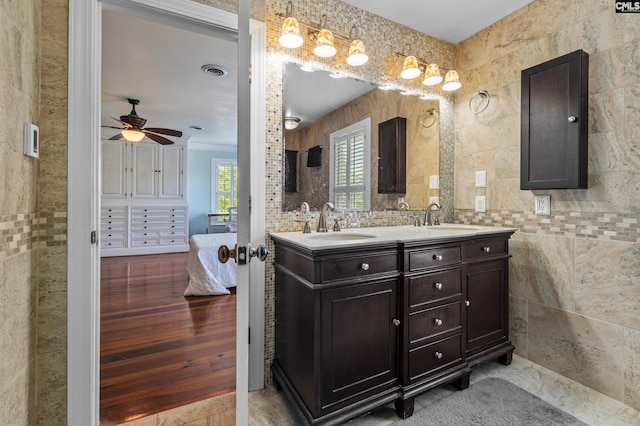 bathroom with ceiling fan, tile walls, vanity, and crown molding