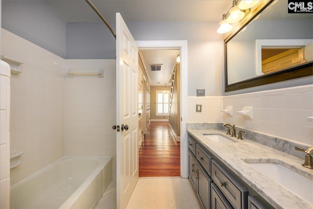 bathroom with vanity, tile walls, tile patterned floors, and tiled shower / bath