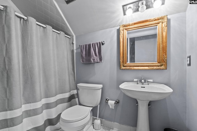 bathroom with toilet, lofted ceiling, and a shower with curtain