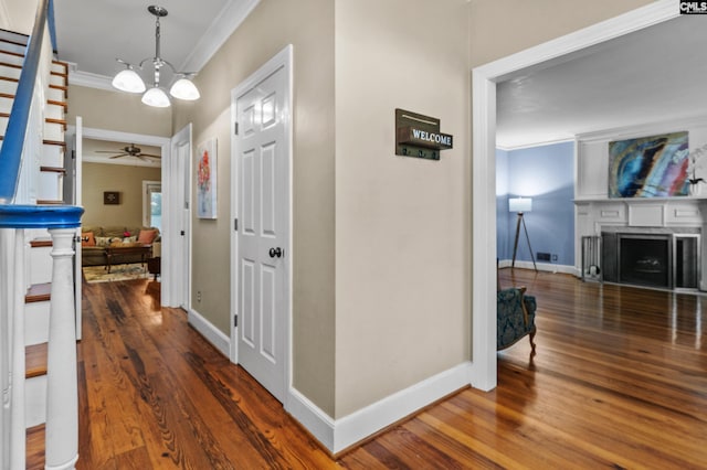 hall featuring dark hardwood / wood-style flooring, ornamental molding, and a notable chandelier