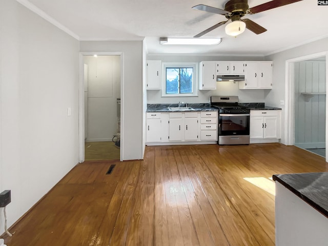 kitchen with hardwood / wood-style floors, stainless steel gas range oven, sink, ceiling fan, and white cabinetry