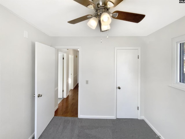 unfurnished bedroom with dark colored carpet and ceiling fan