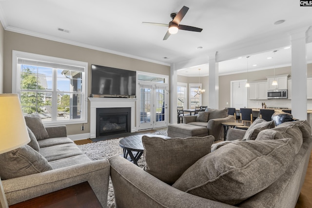 living room featuring wood-type flooring, ceiling fan with notable chandelier, and crown molding