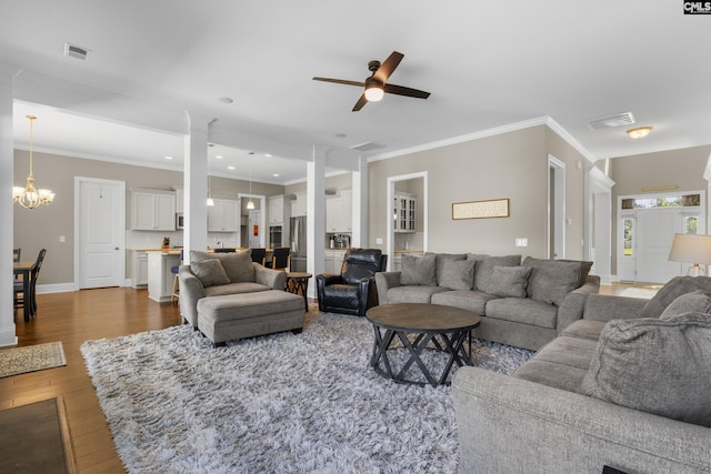 living room with wood-type flooring, ceiling fan with notable chandelier, and ornamental molding