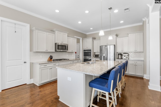 kitchen with a kitchen island with sink, white cabinets, light stone counters, and appliances with stainless steel finishes