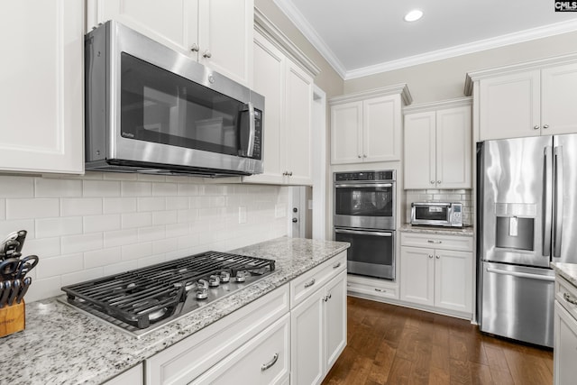 kitchen with backsplash, crown molding, light stone countertops, white cabinetry, and stainless steel appliances