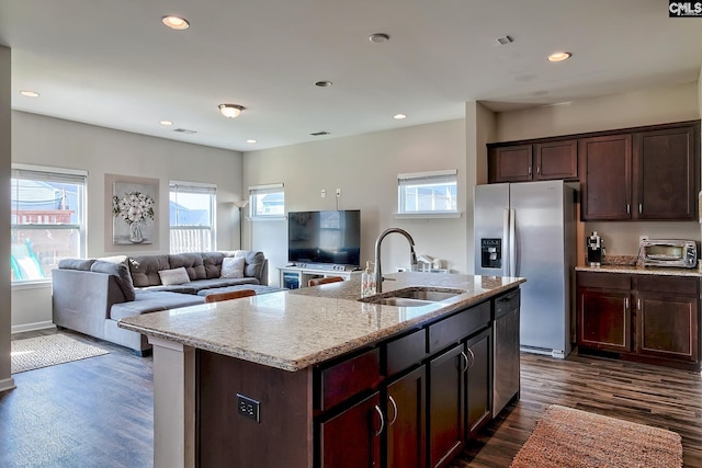 kitchen featuring light stone countertops, appliances with stainless steel finishes, sink, a center island with sink, and dark hardwood / wood-style floors