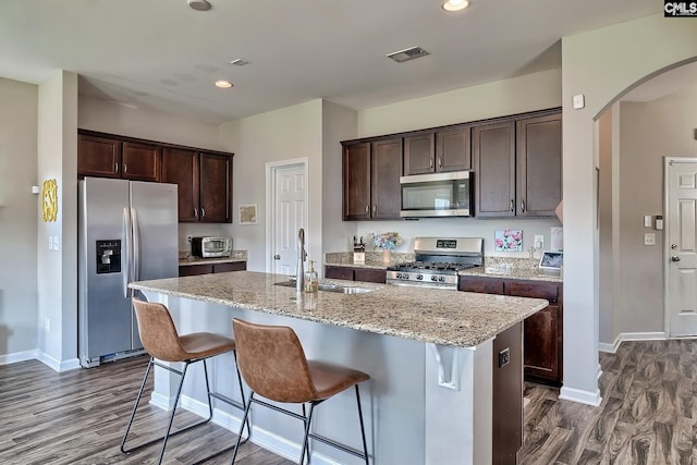 kitchen featuring sink, dark brown cabinetry, stainless steel appliances, and an island with sink