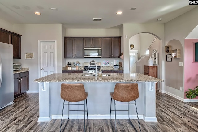 kitchen with dark brown cabinetry, a center island with sink, stainless steel appliances, and sink