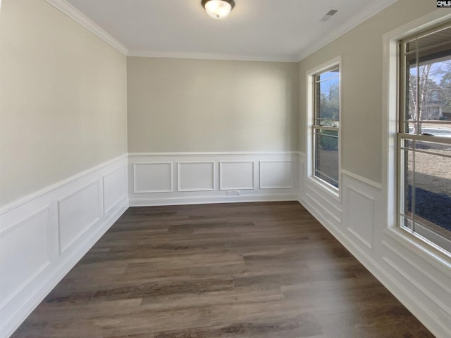 empty room with dark hardwood / wood-style floors, a wealth of natural light, and ornamental molding