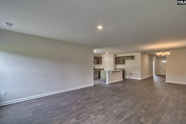 unfurnished living room with an inviting chandelier and dark hardwood / wood-style flooring