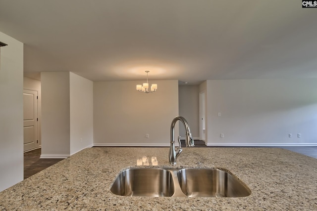 kitchen featuring sink, a chandelier, light stone counters, and decorative light fixtures