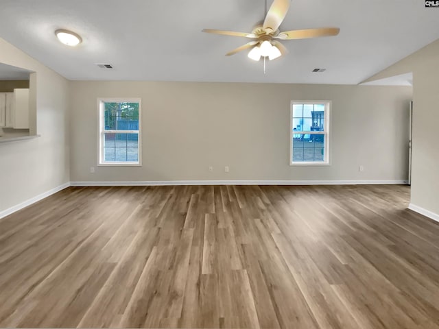 spare room featuring hardwood / wood-style floors, vaulted ceiling, a wealth of natural light, and ceiling fan