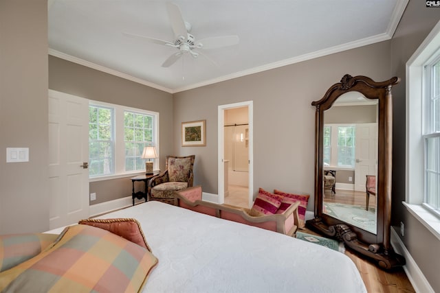 bedroom with connected bathroom, ceiling fan, wood-type flooring, and multiple windows