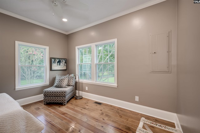 living area featuring electric panel, ceiling fan, ornamental molding, and hardwood / wood-style flooring