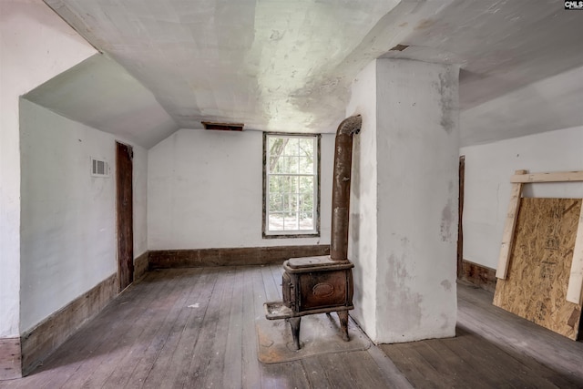 bonus room with wood-type flooring, a wood stove, and vaulted ceiling