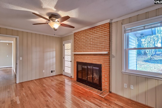 unfurnished living room with a fireplace, a wealth of natural light, ceiling fan, and crown molding