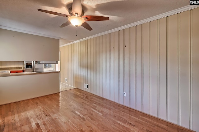 spare room featuring crown molding, light hardwood / wood-style flooring, ceiling fan, and a textured ceiling