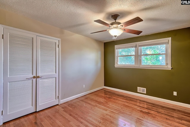 unfurnished bedroom with a textured ceiling, light wood-type flooring, a closet, and ceiling fan