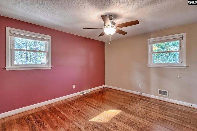 unfurnished room featuring hardwood / wood-style flooring, ceiling fan, a healthy amount of sunlight, and a textured ceiling